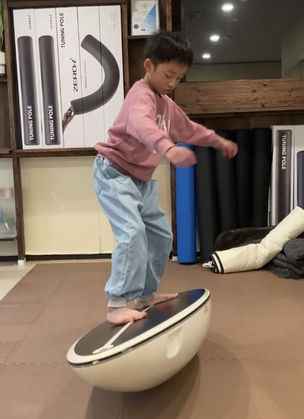 男の子が形の違うバランスボードの上でひざを曲げてバランスをとる様子