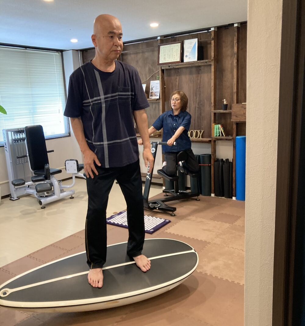 サーフトレーナーでバランスを整える男性と、マシンでストレッチする女性