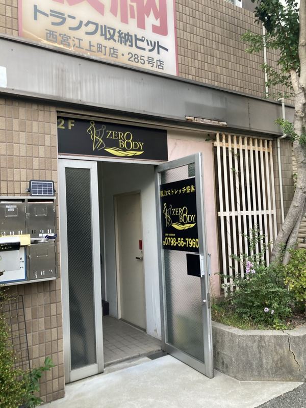 ZEROBODYの入口。金色のロゴの看板と2Fの表示がある建物の入口