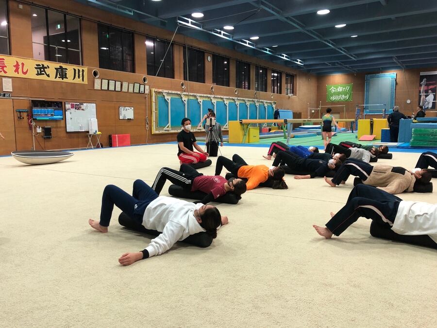 体育館でポールを使った脱力ストレッチを指導する様子