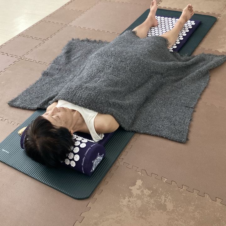 シャクティマットの上にあお向けに横になり、ブランケットをかけて全身の力を抜く様子