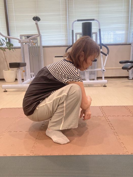 かかとをつけて深くしゃがむシニアの女性