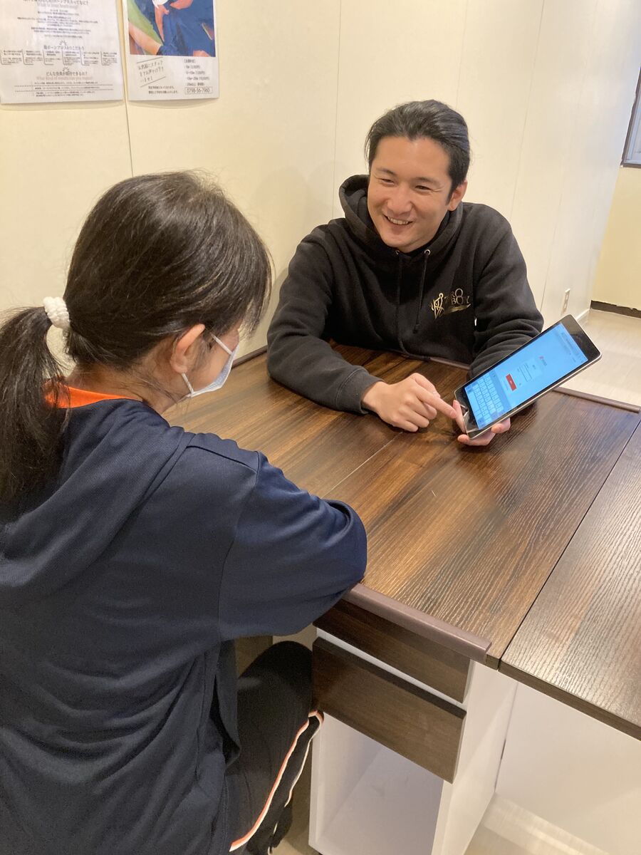 タブレットを使いながら笑顔で説明する院長