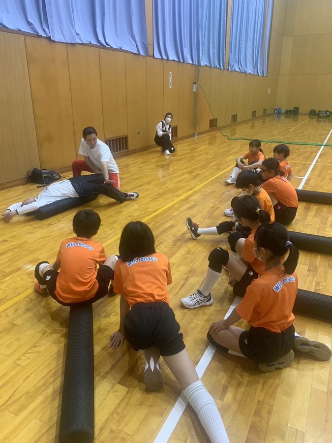 体育館で、子どもたちのスポーツチームにストレッチポールを使った脱力ストレッチを指導する様子